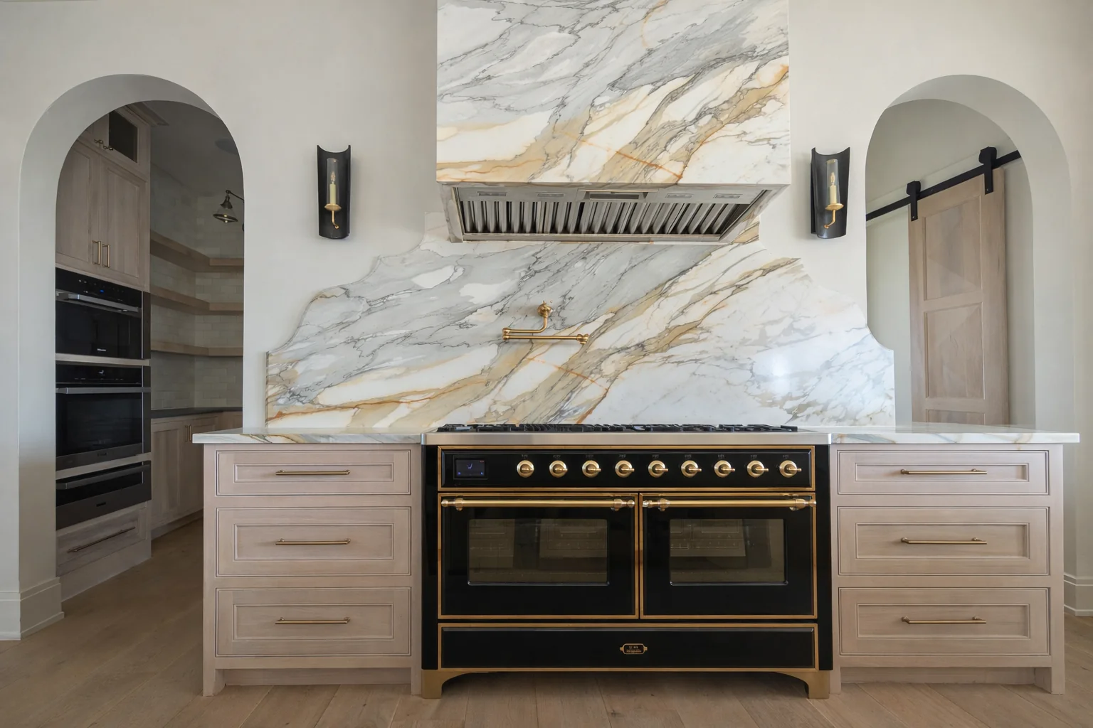 Kitchen with a sculptural marble range hood, warm cabinetry, and brass details